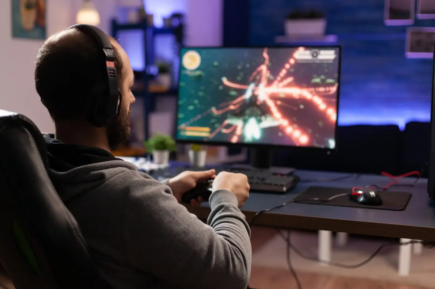 A man wearing a headset playing a video game at a home desk